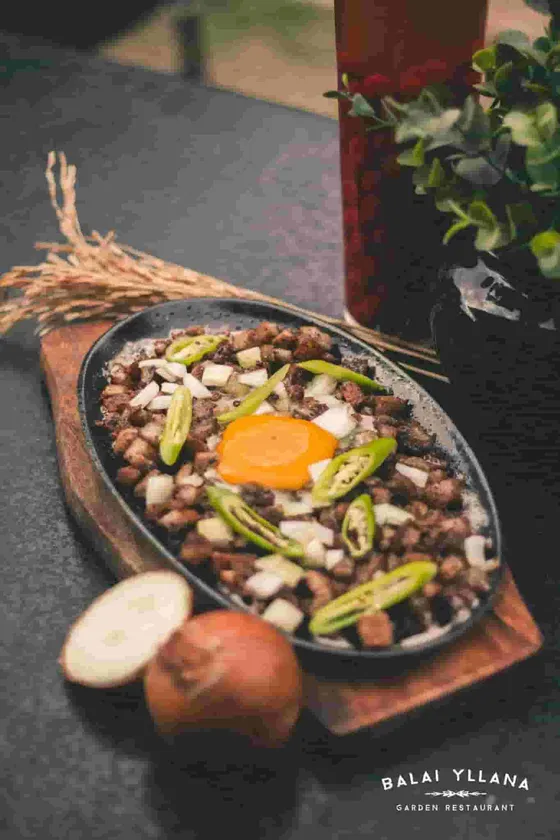 Sisig on a sizzling plate with egg and sliced chili, 2017