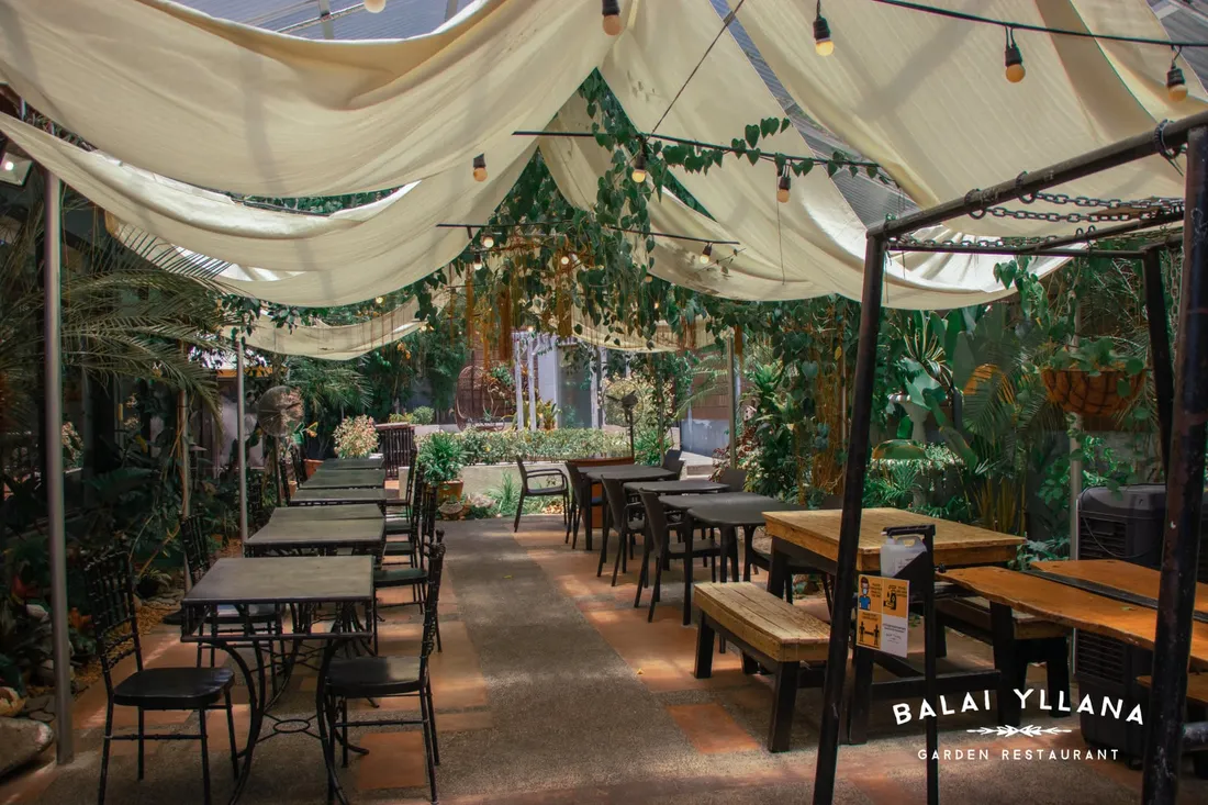 Long rows of tables under draped fabric canopies in the garden, 2021