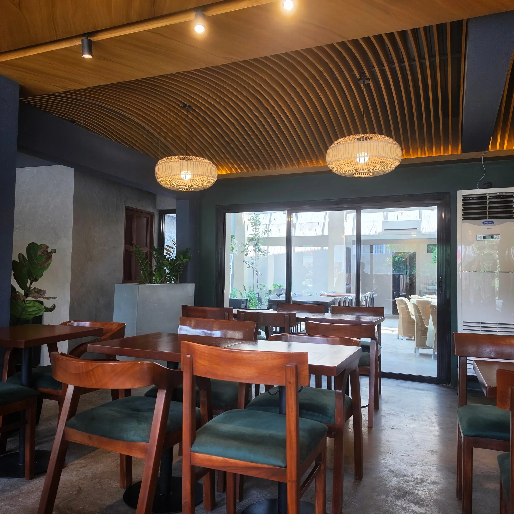 The Hapag dining room: wooden tables and green seats under woven pendant lamps and a slatted wood ceiling