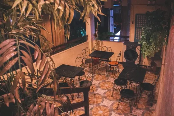The terrace at night, with iron chairs and tables on patterned tiles, 2017